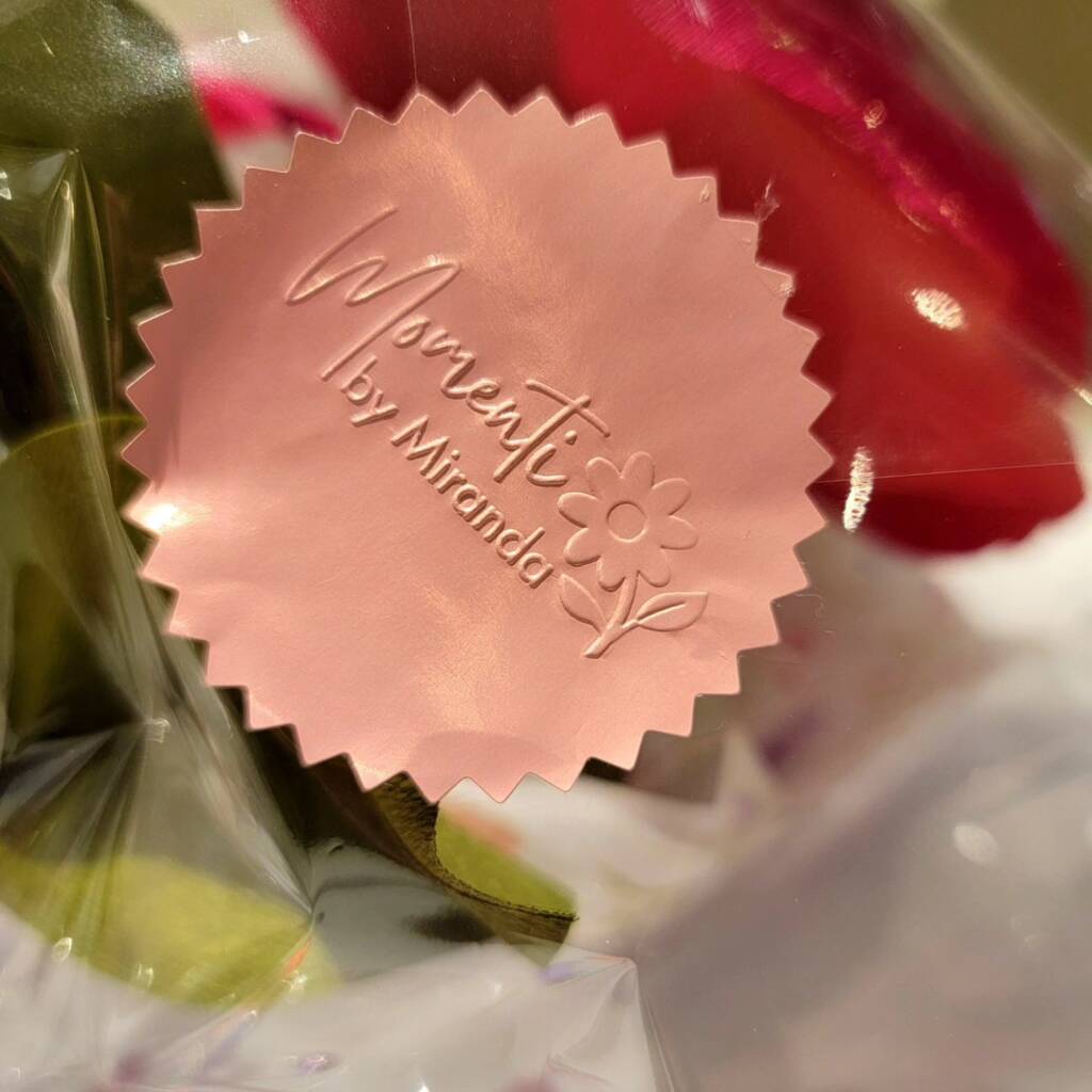 Pink sticker with Momenti by Miranda embossed.